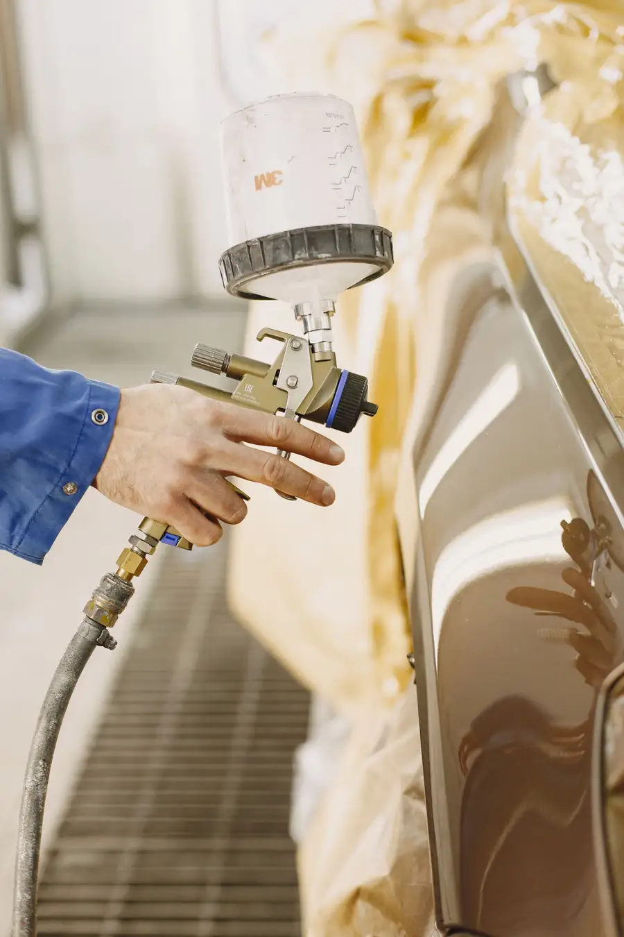 Spray gun applying paint to a car panel