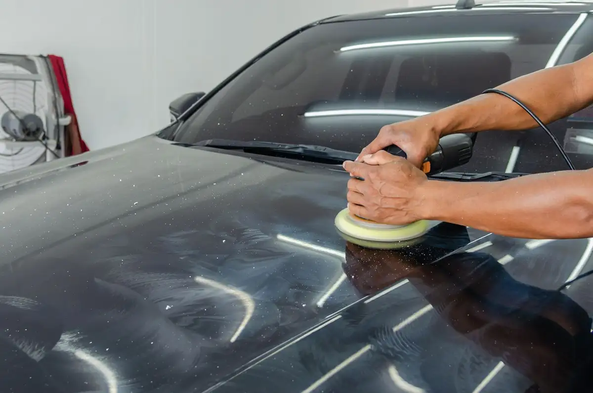 Machine polishing a dark car's hood to a mirror finish